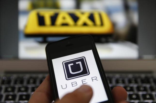 An illustration picture shows the logo of car-sharing service app Uber on a smartphone next to the picture of an official German taxi sign in Frankfurt, September 15, 2014.  REUTERS/Kai Pfaffenbach