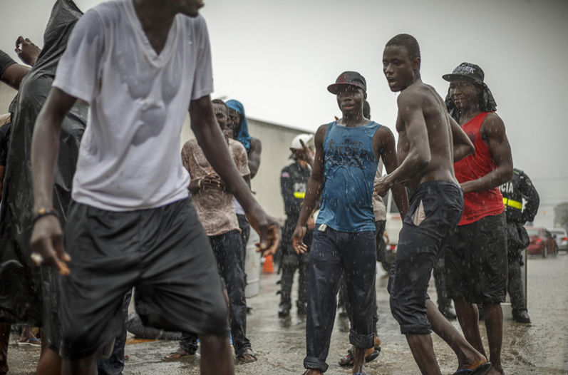 Some of the 200 African migrants caught in the downpour that fell on Paseo Canoas Saturday afternoon danced and sang in the rain, while others took cover without regard to the police presence. Photo Andres Arce, La Nacion